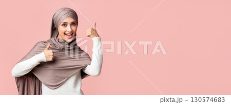 I Like It. Happy Arabic Girl In Hijab Gesturing Thumb Up With Both Hands Over Pink Background, Free Space I Like It. Happy Arabic Girl In Hijab Gesturing Thumb Up With Both Hands Over Pink Background, Free Space 130574683