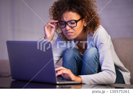 African-american student girl with bad eyesight using laptop, trying to make homework African-american student girl with bad eyesight using laptop, trying to make homework 130575261
