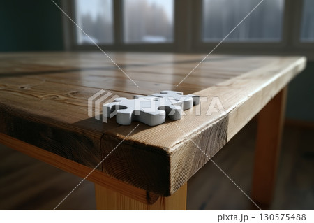 Puzzle piece resting on a wooden table with natural light illuminating the space 130575488