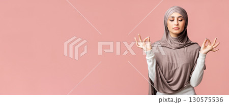 Zen. Relaxed muslim girl in hijab meditating with closed eyes, holding her fingers in mudra gesture over pink background with empty space 130575536