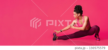 Athletic afro girl stretching legs before training over red background, panorama with copy space, banner for website 130575579