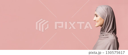 Profile portrait of beautiful muslim girl in hijab looking at copy space over pink background 130575617