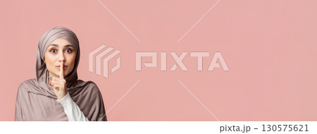Secret Concept. Young arabic woman in hijab showing hush sign, putting finger on lips, gesturing keep silence over pink studio background, empty space Secret Concept. Young arabic woman in hijab showing hush sign, putting finger on lips, gesturing keep silence over pink studio background, empty space 130575621