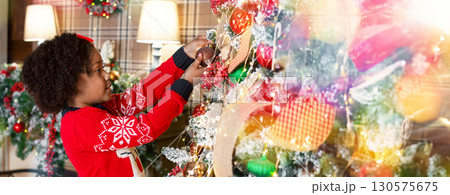 Xmas tradition. Cute little african american girl decorating Christmas tree at home, panorama Xmas tradition. Cute little african american girl decorating Christmas tree at home, panorama 130575675