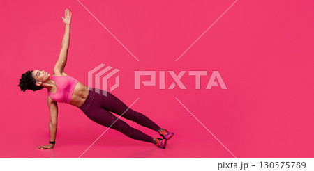 Concentrated sporty black woman practicing yoga or planking over red background, copy space 130575789