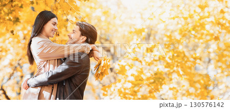 Joyful man and woman in love hugging at golden park, free space 130576142