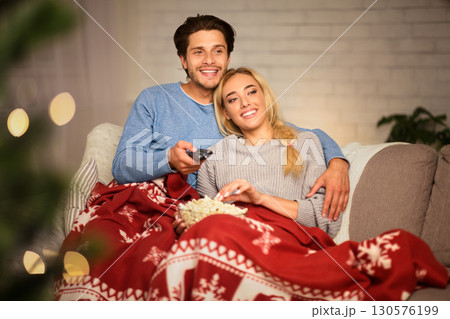 Couple in love at Christmas eve enjoying popcorn and watching tv at home Couple in love at Christmas eve enjoying popcorn and watching tv at home 130576199