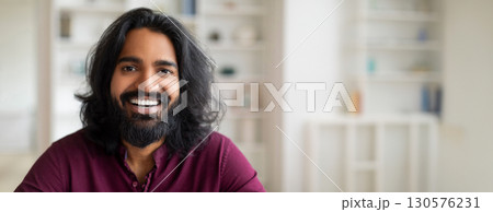 Portrait of handsome cheerful young indian man looking at camera, positive millennial eastern male posing indoors in home interior, closeup shot of smiling bearded millennial guy, copy space 130576231