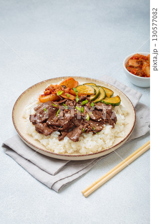 Korean beef bulgogi bowl dish with rice, roasted meat, kimchi and marinated cucumber on white background with chopsticks Korean beef bulgogi bowl dish with rice, roasted meat, kimchi and marinated cucumber on white background with chopsticks 130577082