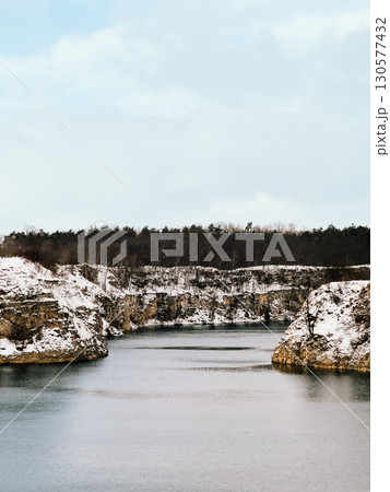 Snow covered limestone cliffs surround tranquil lake in winter landscape, featuring scenic beauty, creating serene and picturesque scene. Limestone cliffs rising above snow blanketed lake surface Snow covered limestone cliffs surround tranquil lake in winter landscape, featuring scenic beauty, creating serene and picturesque scene. Limestone cliffs rising above snow blanketed lake surface 130577432