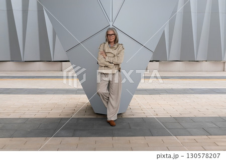 Confident person standing near modern architectural structure in urban setting on sunny day 130578207