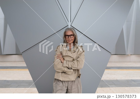 Modern woman poses confidently in urban setting with geometric architecture in the background during Modern woman poses confidently in urban setting with geometric architecture in the background during 130578373