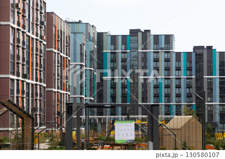 Modern high-rise apartment buildings in a vibrant residential area with gardens and playgrounds 130580107