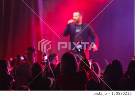 Fans capturing live concert performance on their mobile devices in a vibrant setting 130580216