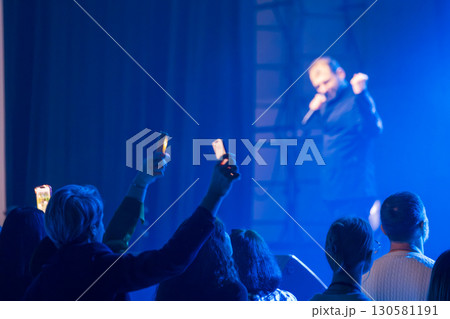 Audience enjoying live concert raising illuminated phones towards stage Audience enjoying live concert raising illuminated phones towards stage 130581191