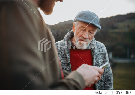 Man showing older person something in smartphone. Man showing older person something in smartphone. 130581362