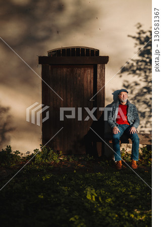 Older man enjoying warm autumn sun in face, sitting on bench. Older man enjoying warm autumn sun in face, sitting on bench. 130581367