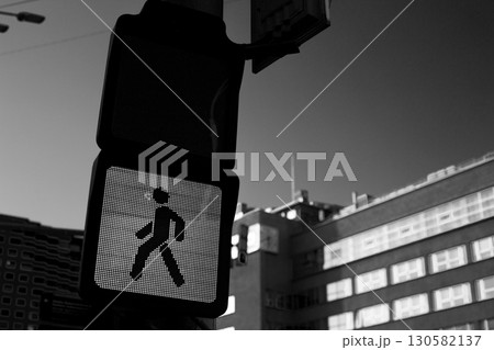 Black and white image of pedestrian signal depicting walking figure, need for caution in urban environments. Hidden dangers of traffic and significance of personal responsibility in road safety 130582137