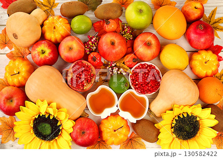 Thanksgiving banner, autumn background with apples, pomegranates, pumpkins, honey, grapes, flowers under sunflowers and leaves on wooden table, harvest concept, healthy natural food advertising, 130582422
