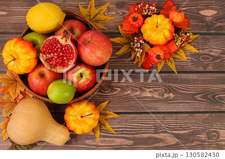 Harvest concept, Thanksgiving banner, autumn background with apples, pomegranates, pumpkins, honey, grapes, flowers under sunflowers and leaves on wooden table, healthy natural food advertisement. 130582430