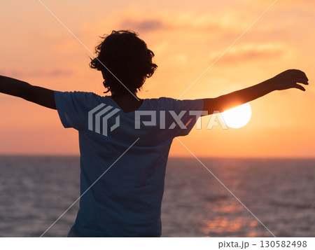 Person with Arms Stretched Out at a Sunset 130582498