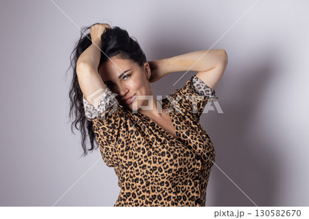 Woman is shown from the waist up, wearing a leopard print top, with her arms  130582670