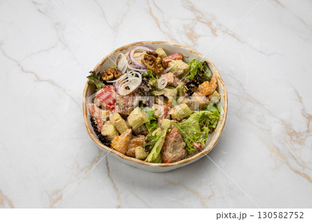 Traditional Georgian salad with vegetables, walnuts, and creamy dressing in ceramic bowl 130582752