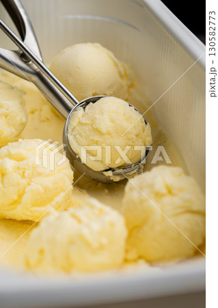 Vanilla ice cream scoops in tray with scoop utensil, close-up food background Vanilla ice cream scoops in tray with scoop utensil, close-up food background 130582773