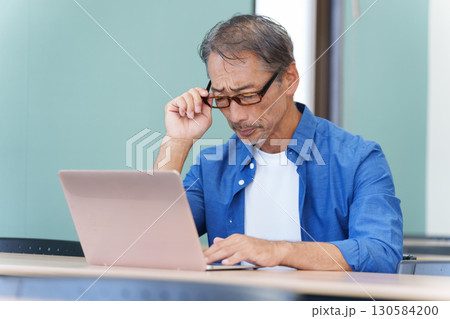 パソコンを使う老眼のシニア男性 130584200