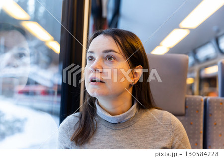 Astonished woman looking through train window while journeying Astonished woman looking through train window while journeying 130584228