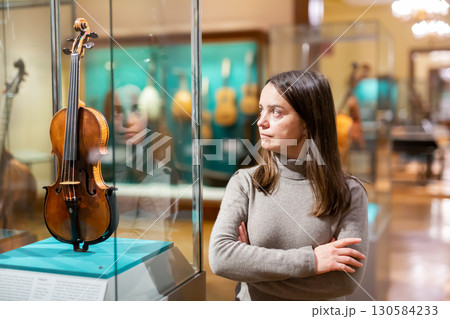 Interested brunette visiting exhibition of medieval musical instruments in museum 130584233