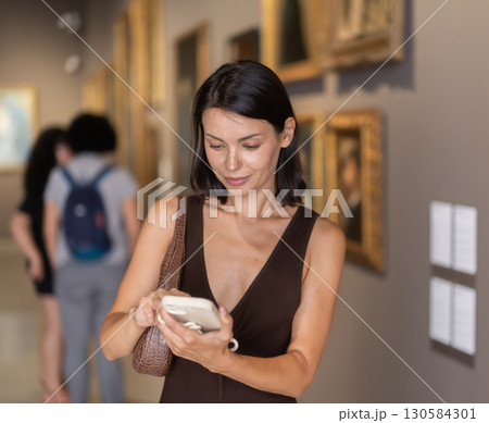 While visiting museum, girl uses travel guide application on her phone. While visiting museum, girl uses travel guide application on her phone. 130584301