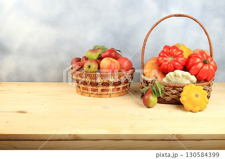 Basket with pumpkins, zucchini and apples on a wooden table. Autumn composition with gifts of nature, thanksgiving day concept, harvesting, banner or splash, postcard, rustic style, selective focus Basket with pumpkins, zucchini and apples on a wooden table. Autumn composition with gifts of nature, thanksgiving day concept, harvesting, banner or splash, postcard, rustic style, selective focus 130584399