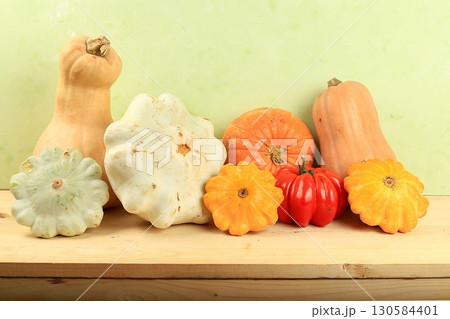 A variety of selection pumpkins, squash and tomatoes on a wooden table. Autumn composition with gifts of nature, thanksgiving day concept, harvesting, banner or splash, postcard, rustic style, 130584401