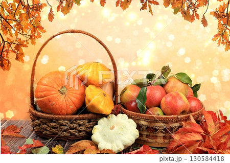 Basket with pumpkins, squash and apples on a wooden table. Autumn abstract composition with oak leaves on blurred bokeh background, thanksgiving day concept, banner or splash, postcard, 130584418