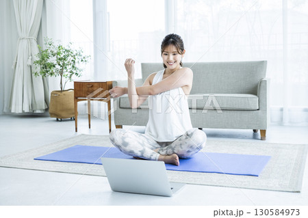 自宅でパソコンを見ながらストレッチする若い女性 130584973