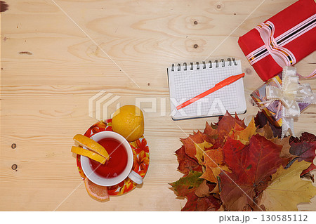 Thanksgiving, autumn background with seasonal maple leaves, a cup of hot tea with lemon and gifts on a wooden background, top view, copy space, flat lay. Happy Thanksgiving concept, selective focus. Thanksgiving, autumn background with seasonal maple leaves, a cup of hot tea with lemon and gifts on a wooden background, top view, copy space, flat lay. Happy Thanksgiving concept, selective focus. 130585112
