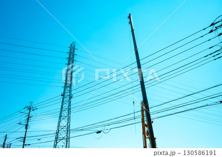 空に伸びるクレーンのアームと送電鉄塔　a-4 ライトカラー 130586191