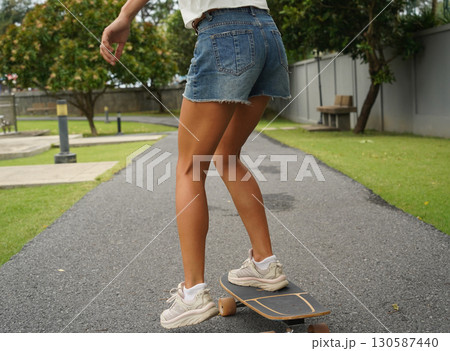 A young woman is skillfully riding a skateboard down a scenic park 130587440
