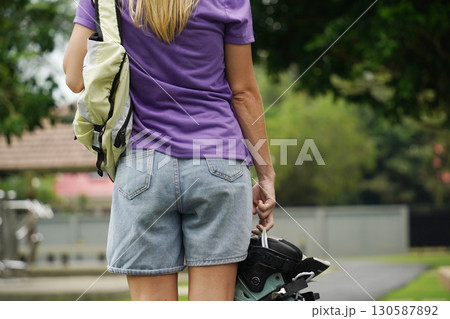 A woman is rollerblading gracefully on a road located in a park A woman is rollerblading gracefully on a road located in a park 130587892