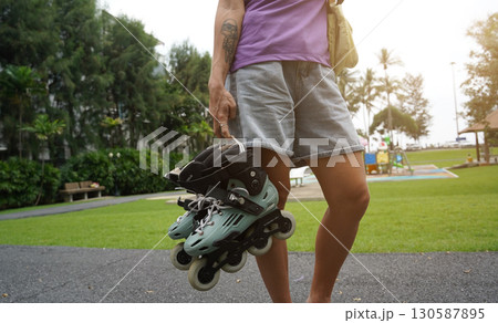 A woman is rollerblading gracefully on a road located in a park 130587895