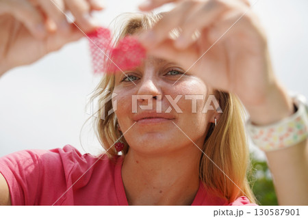 Young woman beading colorful bracelets outdoors in a park 130587901