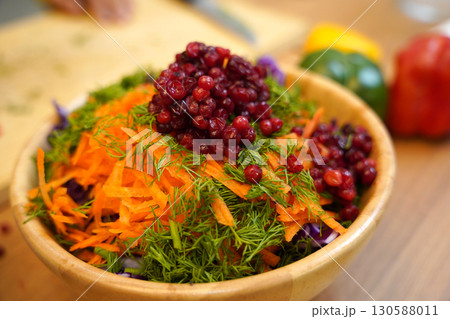A white bowl filled with vibrant carrots, cabbage, and cranberries A white bowl filled with vibrant carrots, cabbage, and cranberries 130588011