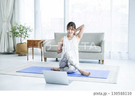 自宅でパソコンを見ながらストレッチをする若い女性 130588110