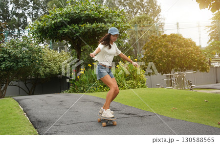 A young woman is skillfully riding a skateboard down a scenic park A young woman is skillfully riding a skateboard down a scenic park 130588565