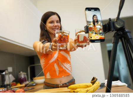 Young woman preparing vegetarian yogurt dessert with papaya and granola Young woman preparing vegetarian yogurt dessert with papaya and granola 130588585