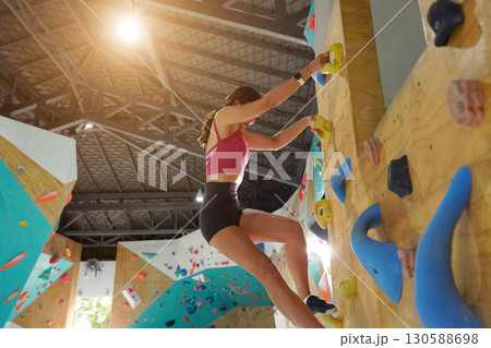 A strong female climber climbs an artificial wall with colorful grips 130588698