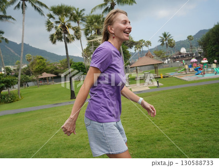A woman is rollerblading gracefully on a road located in a park A woman is rollerblading gracefully on a road located in a park 130588733