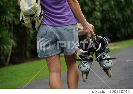 A woman is rollerblading gracefully on a road located in a park 130588746