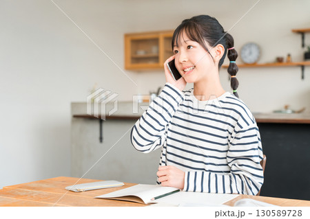 自宅のリビングでスマホで通話する小学生,中学生の女の子 自宅のリビングでスマホで通話する小学生,中学生の女の子 130589728